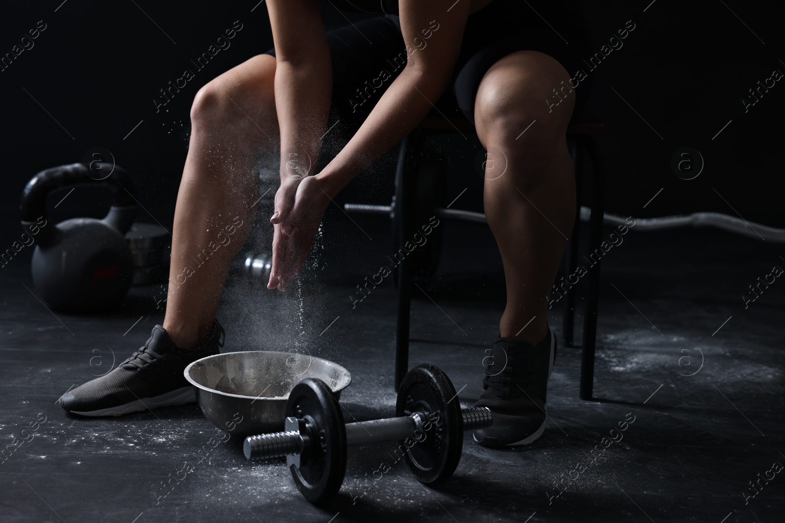 Photo of Woman applying talcum powder onto hands before training in gym, closeup