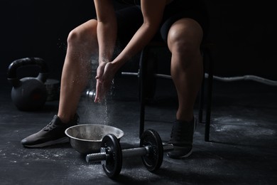 Woman applying talcum powder onto hands before training in gym, closeup