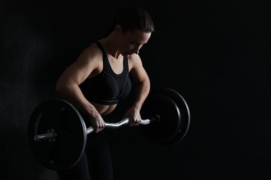 Photo of Woman training with barbell against black background