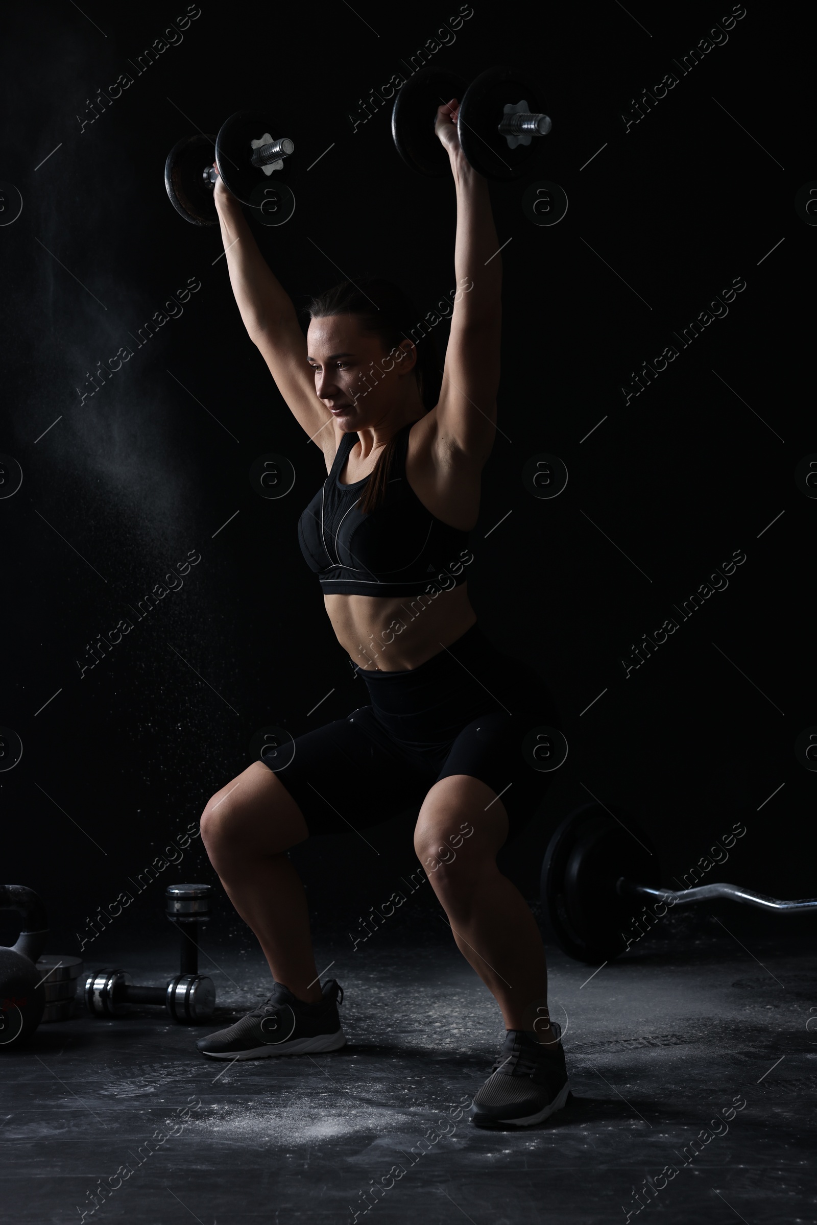 Photo of Woman training with barbells on black background