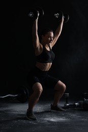 Photo of Woman training with barbells on black background