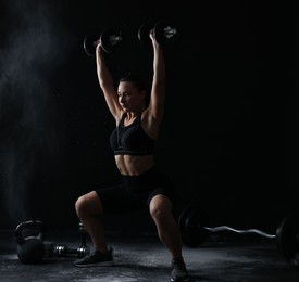 Photo of Woman training with barbells on black background