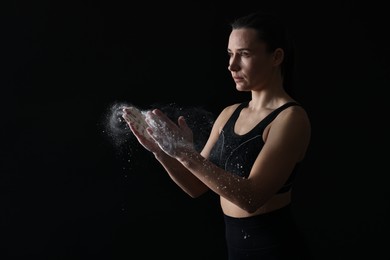 Photo of Woman clapping hands with talcum powder before training on black background