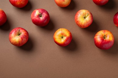 Photo of Ripe red apples on brown background, flat lay