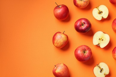 Whole and cut fresh red apples on orange background, flat lay. Space for text