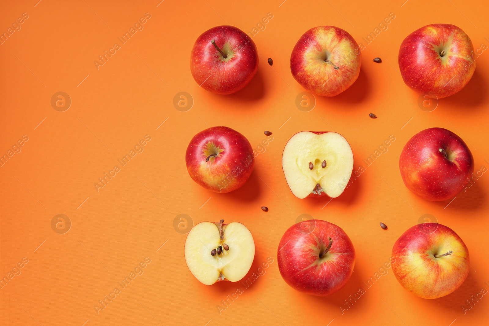 Photo of Fresh red apples and seeds on orange background, flat lay. Space for text