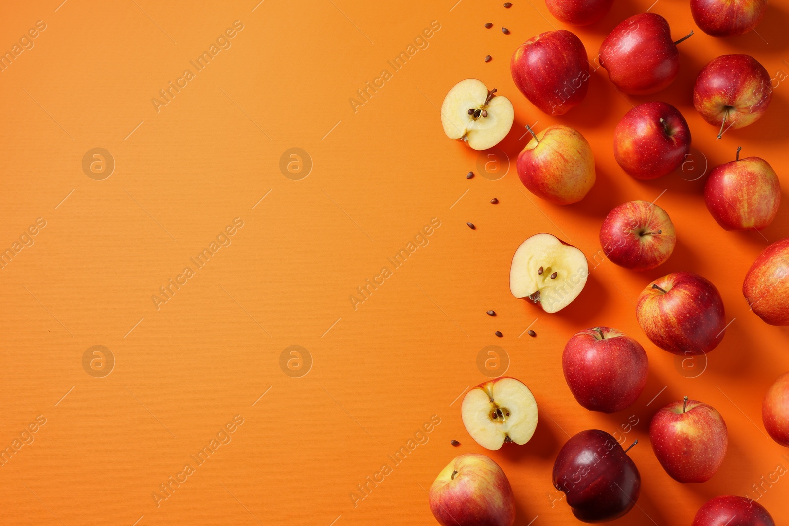 Photo of Fresh red apples and seeds on orange background, flat lay. Space for text