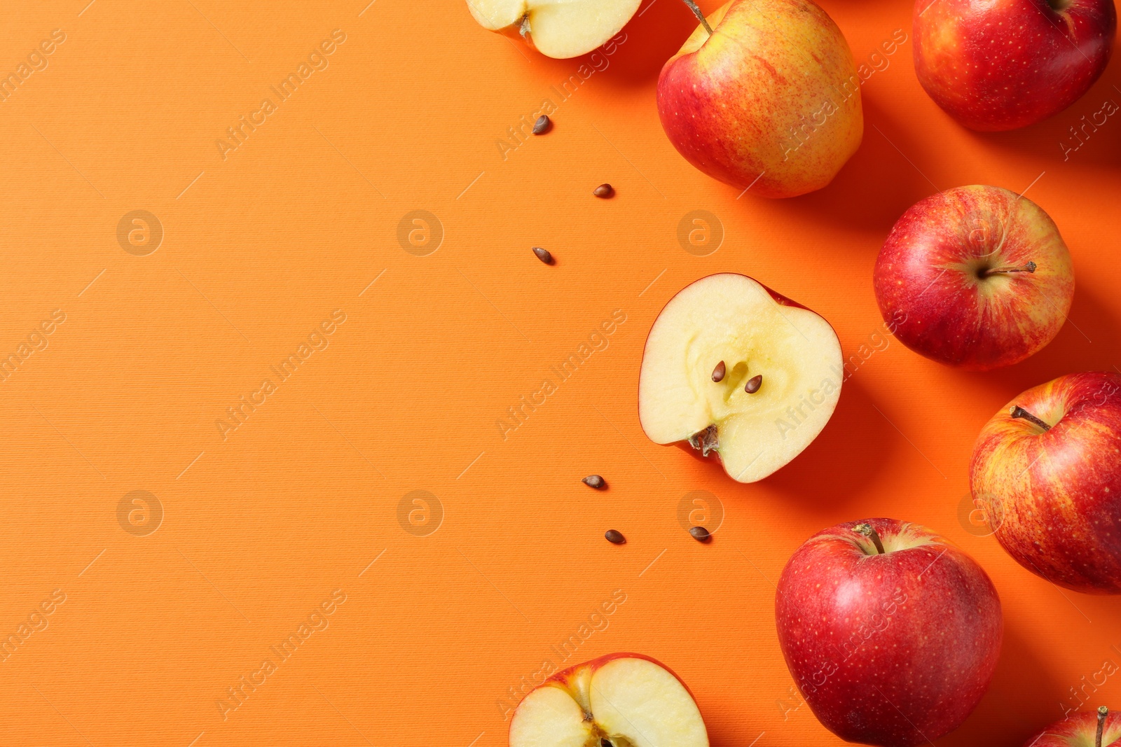 Photo of Fresh red apples and seeds on orange background, flat lay. Space for text