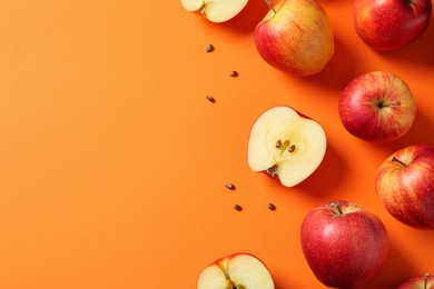 Fresh red apples and seeds on orange background, flat lay. Space for text