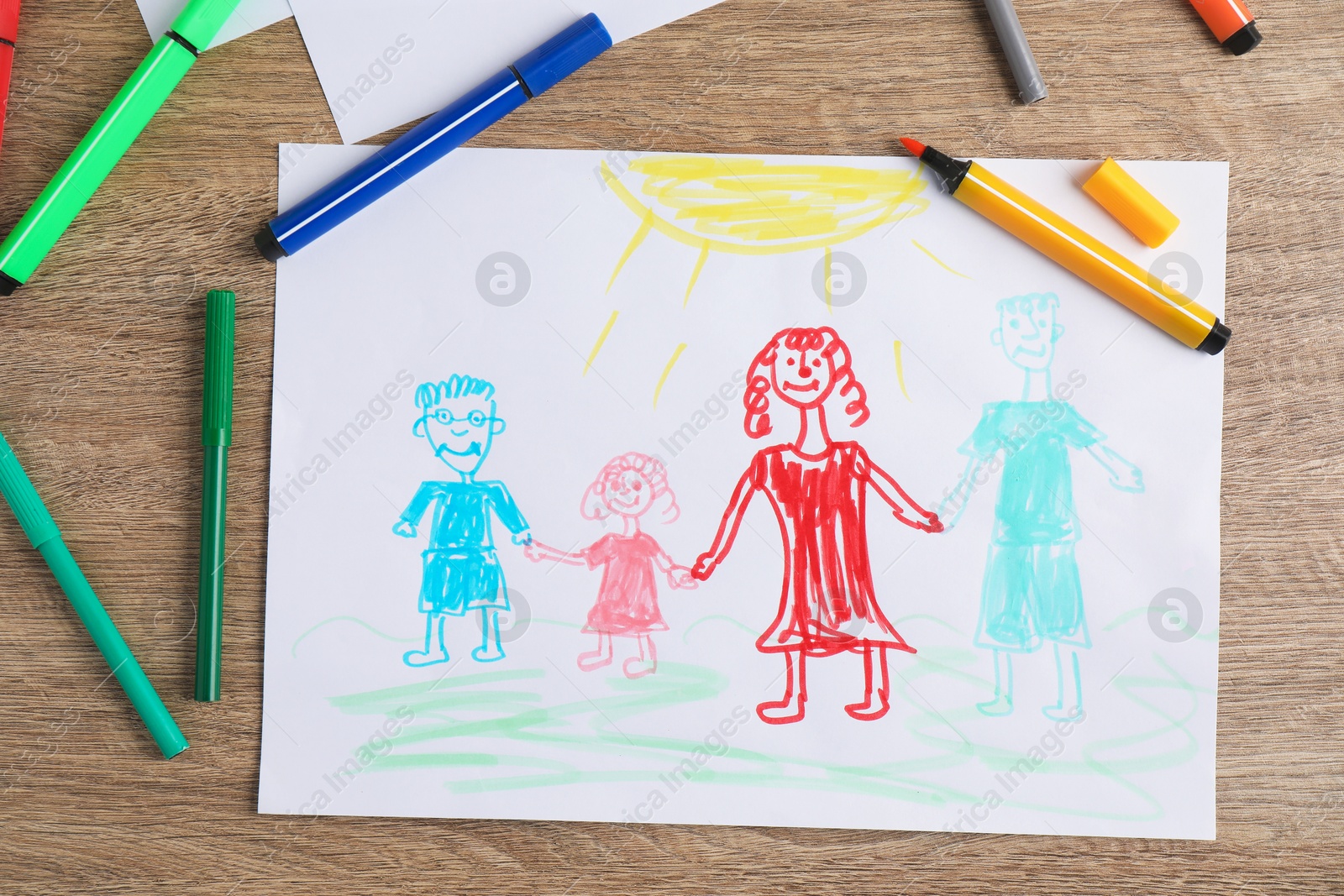 Photo of Child's drawing of happy family and felt tip pens on wooden table, top view