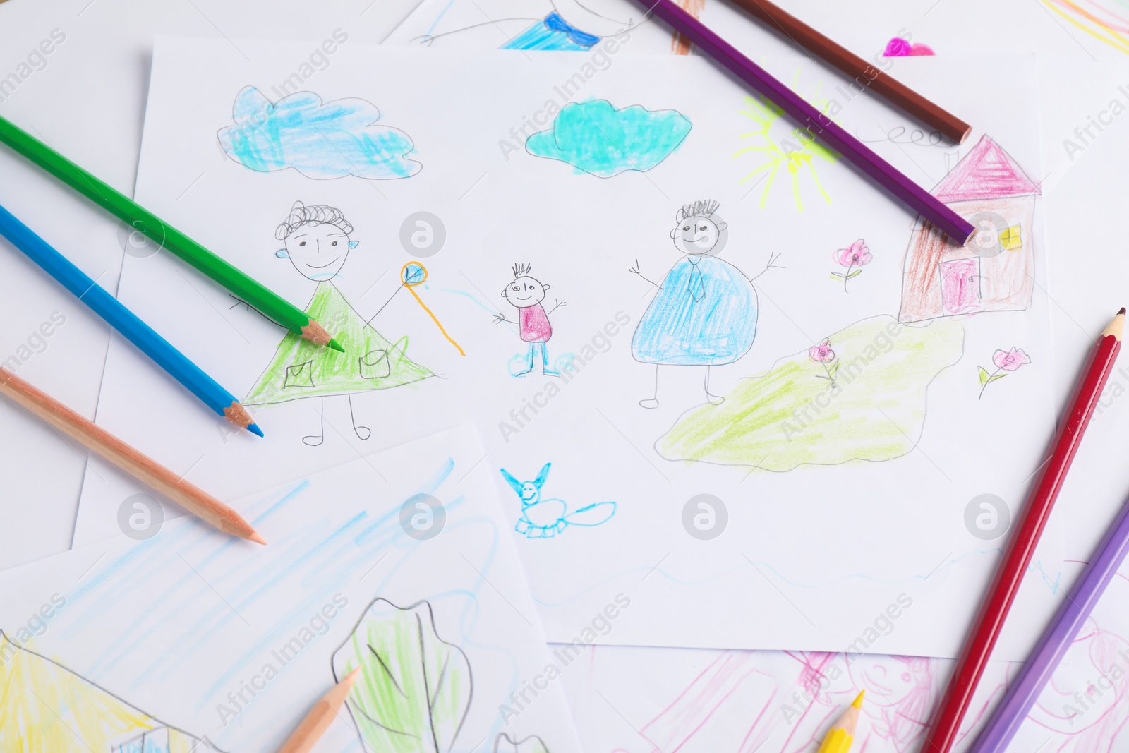 Photo of Child's drawing of happy family and pencils as background, closeup