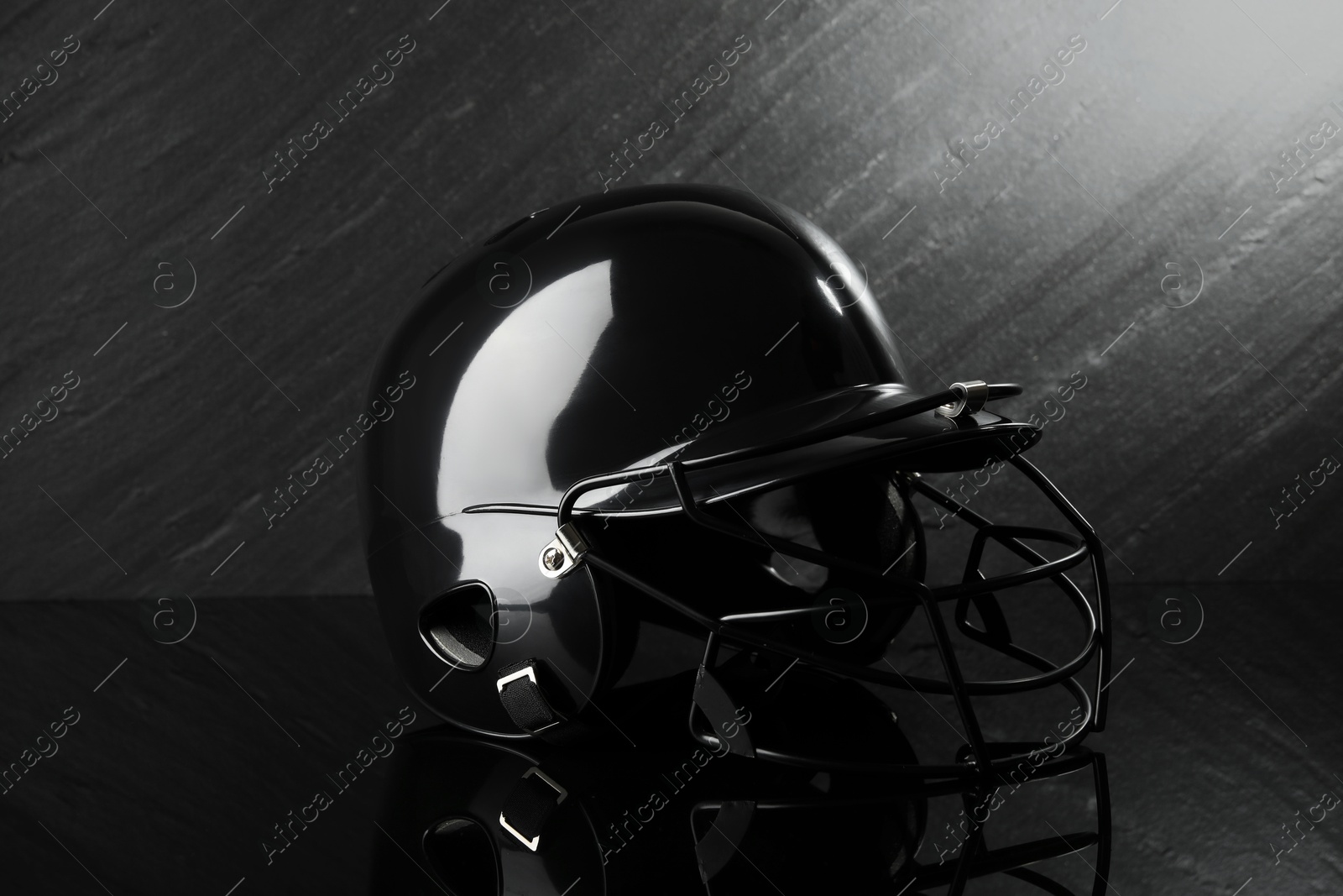 Photo of Black baseball helmet on dark gray background