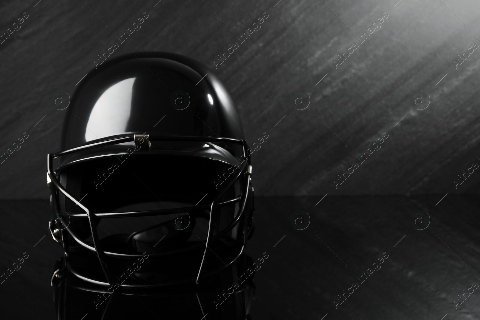 Photo of Black baseball helmet on dark gray background, space for text