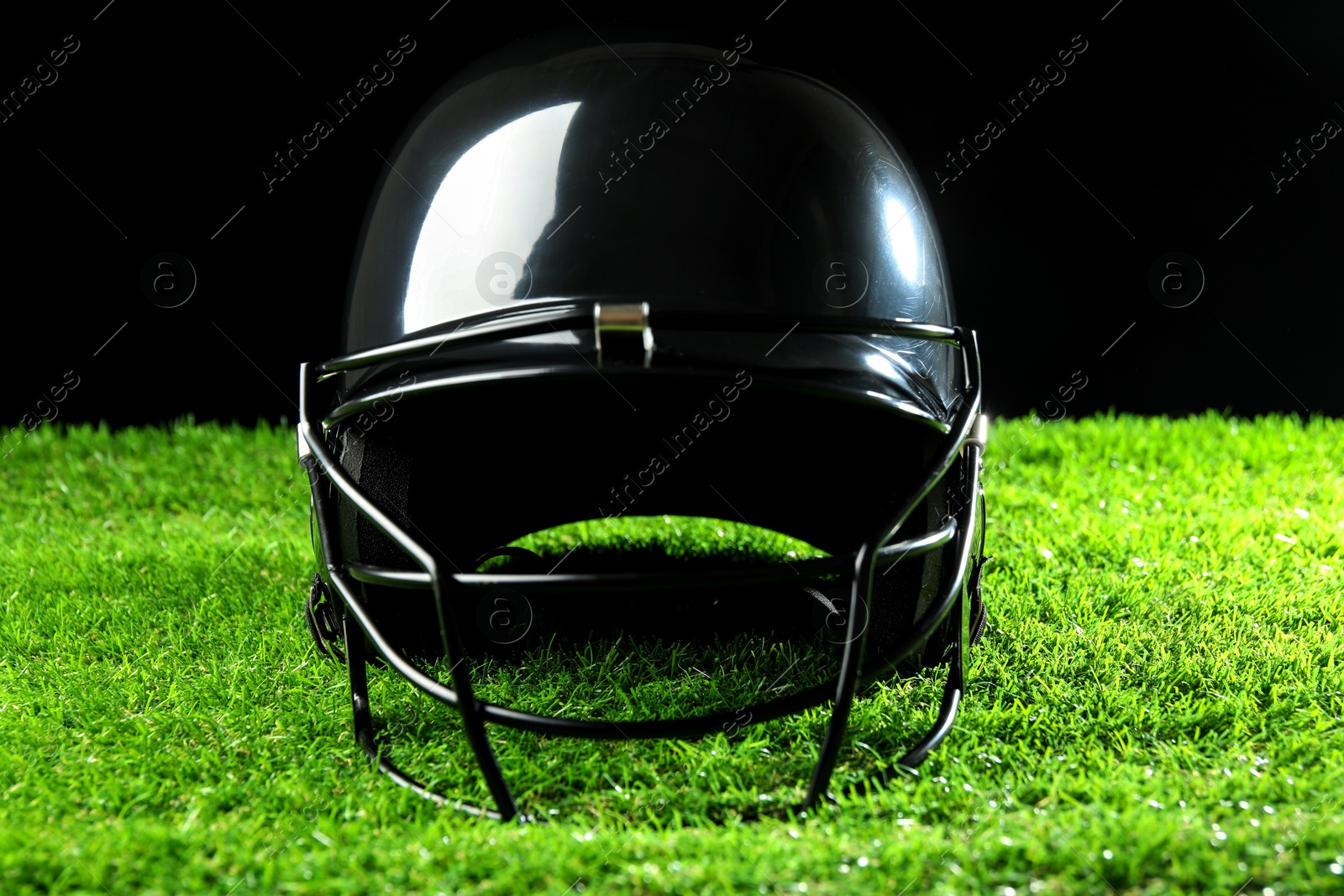 Photo of Baseball helmet on artificial grass against black background