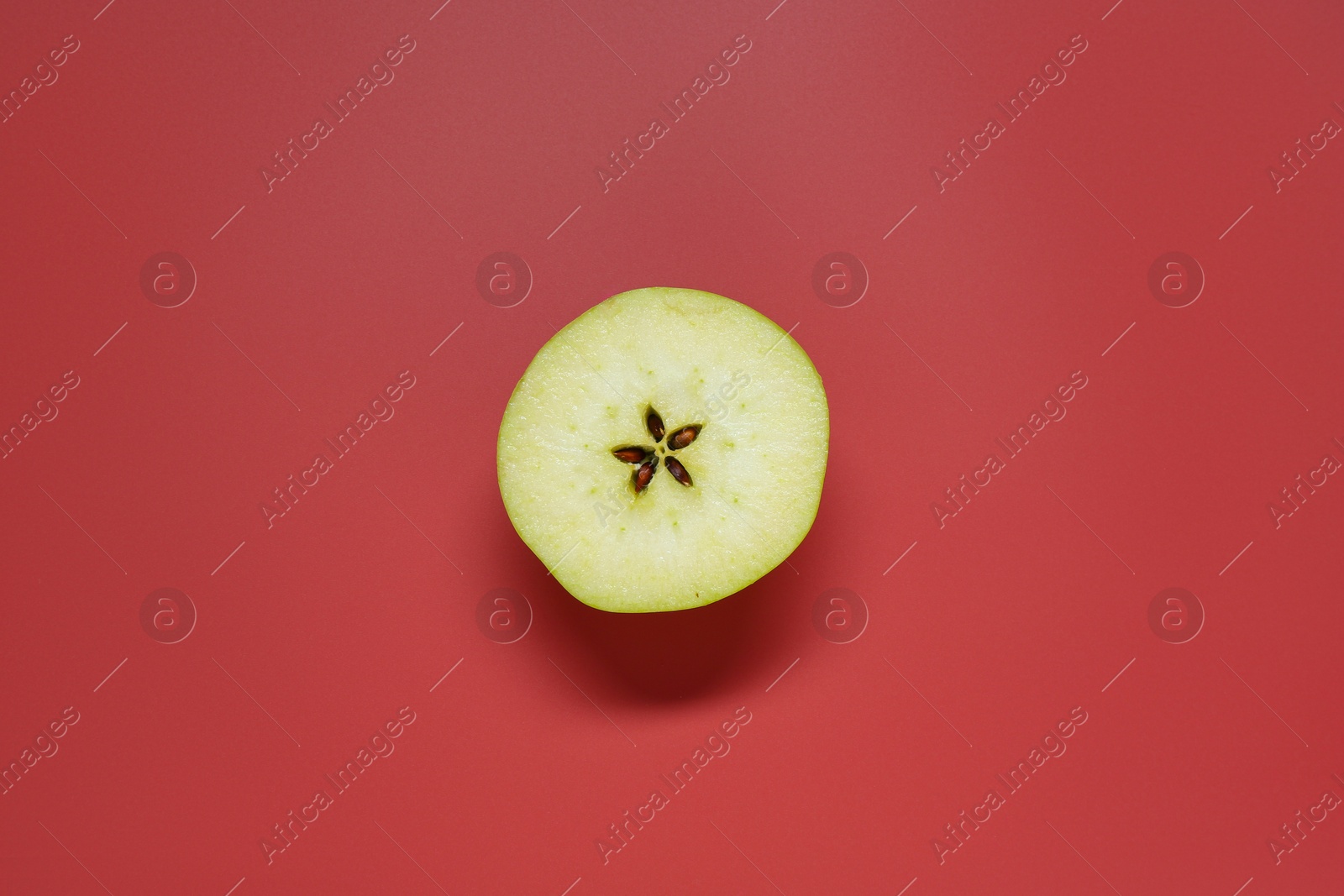 Photo of Half of fresh ripe apple on red background, top view