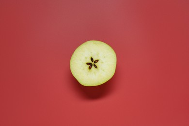 Photo of Half of fresh ripe apple on red background, top view