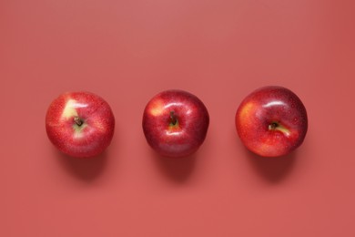 Whole apples on red background, flat lay