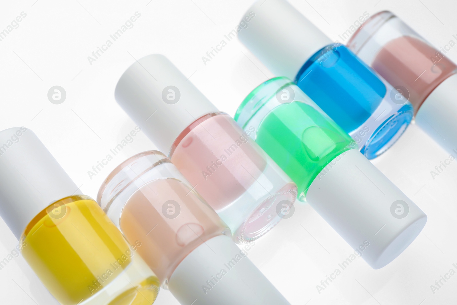 Photo of Nail polishes in bottles on white background, closeup