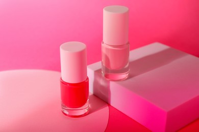 Photo of Nail polish in bottles on pink background, closeup