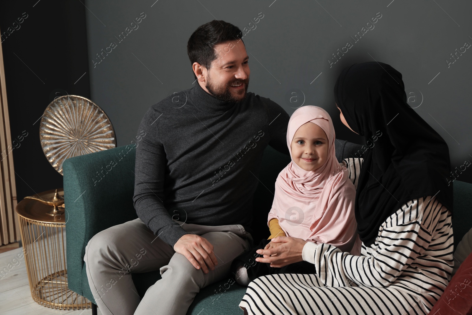 Photo of Happy Muslim family sitting on sofa at home