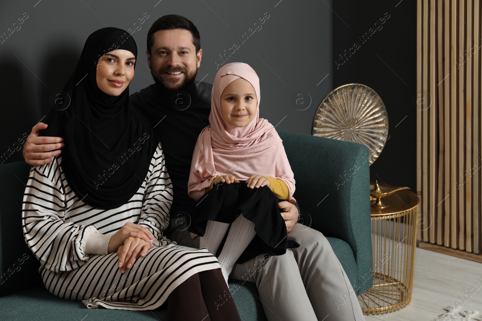 Photo of Happy Muslim family sitting on sofa at home