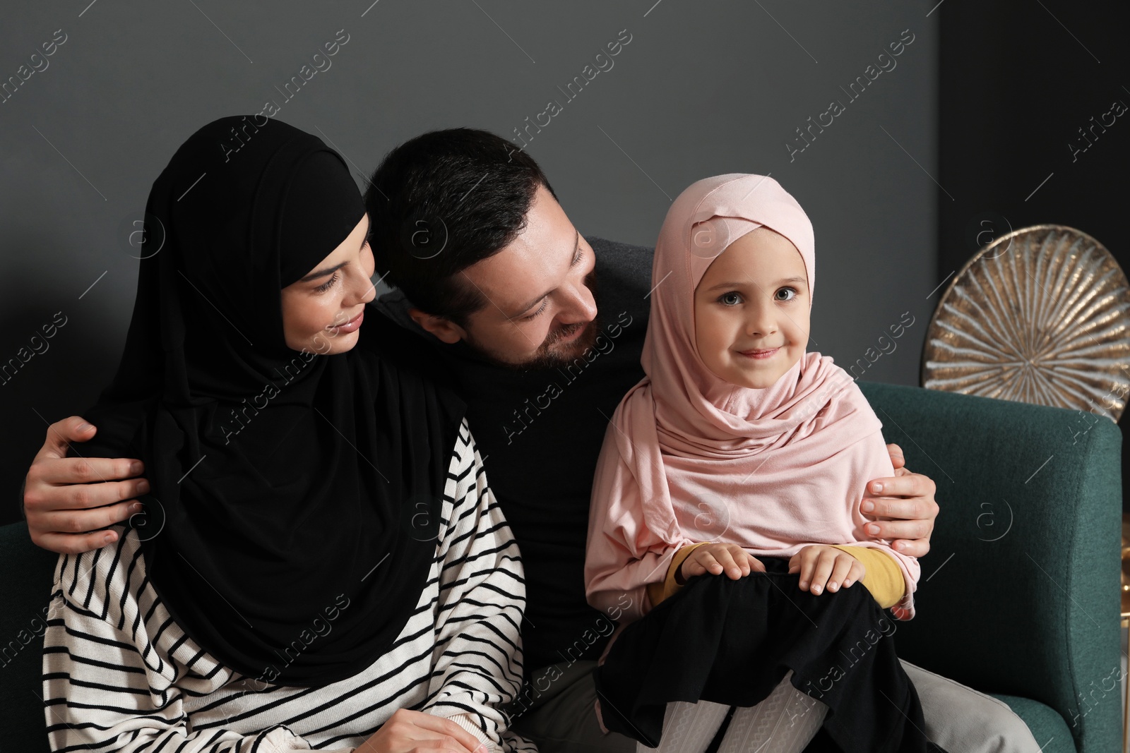 Photo of Happy Muslim family sitting on sofa at home