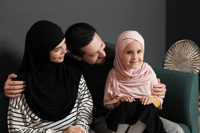 Photo of Happy Muslim family sitting on sofa at home