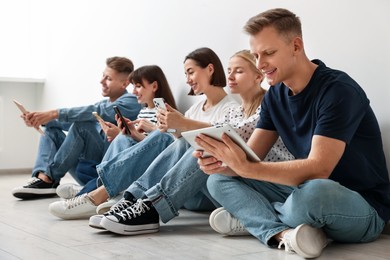 Photo of Group of people using different gadgets on floor indoors. Modern technology