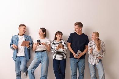 Photo of Group of people using different gadgets near white wall indoors. Modern technology