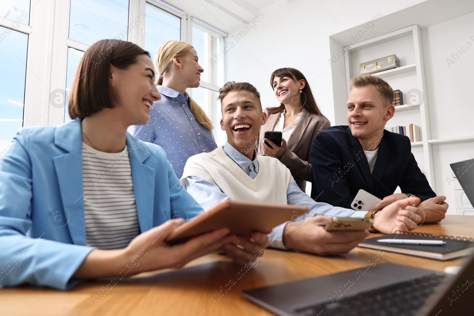 Photo of Group of people using different gadgets at wooden table in office. Modern technology