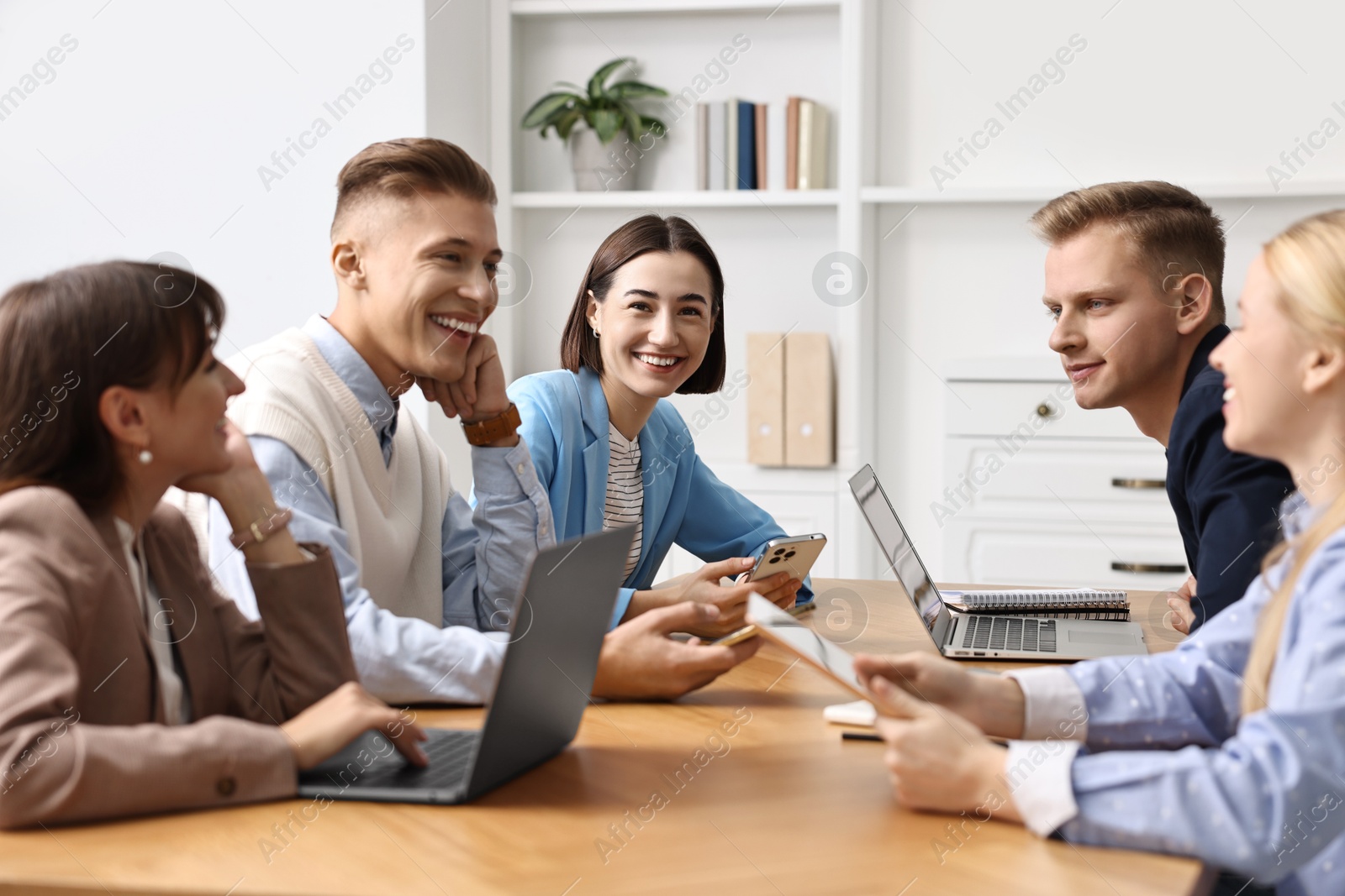 Photo of Group of people using different gadgets at wooden table in office. Modern technology