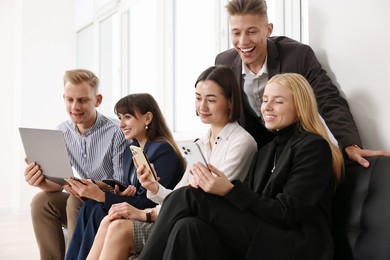 Photo of Group of people using different gadgets near window indoors. Modern technology