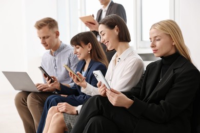 Photo of Group of people using different gadgets near window indoors. Modern technology