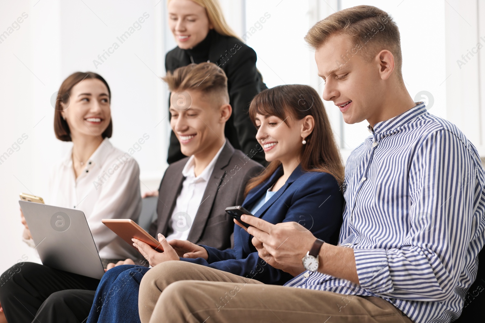 Photo of Group of people using different gadgets near window indoors. Modern technology