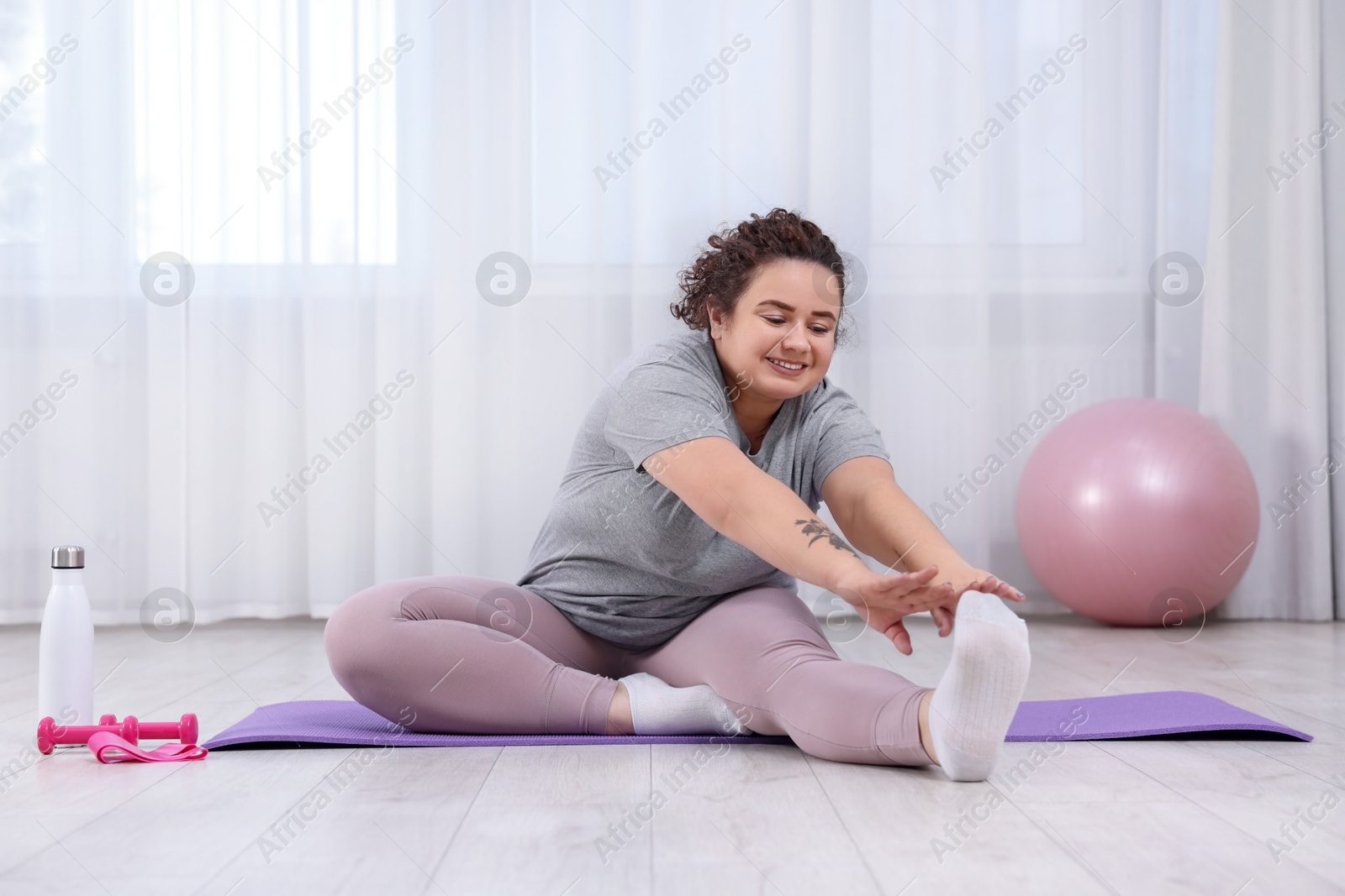 Photo of Woman stretching during training on fitness mat at home