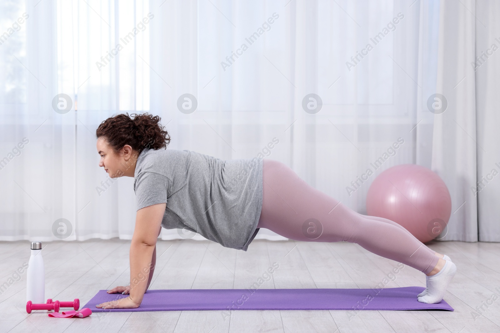 Photo of Woman doing plank exercise on fitness mat at home