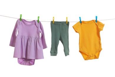 Photo of Different baby clothes drying on laundry line against white background