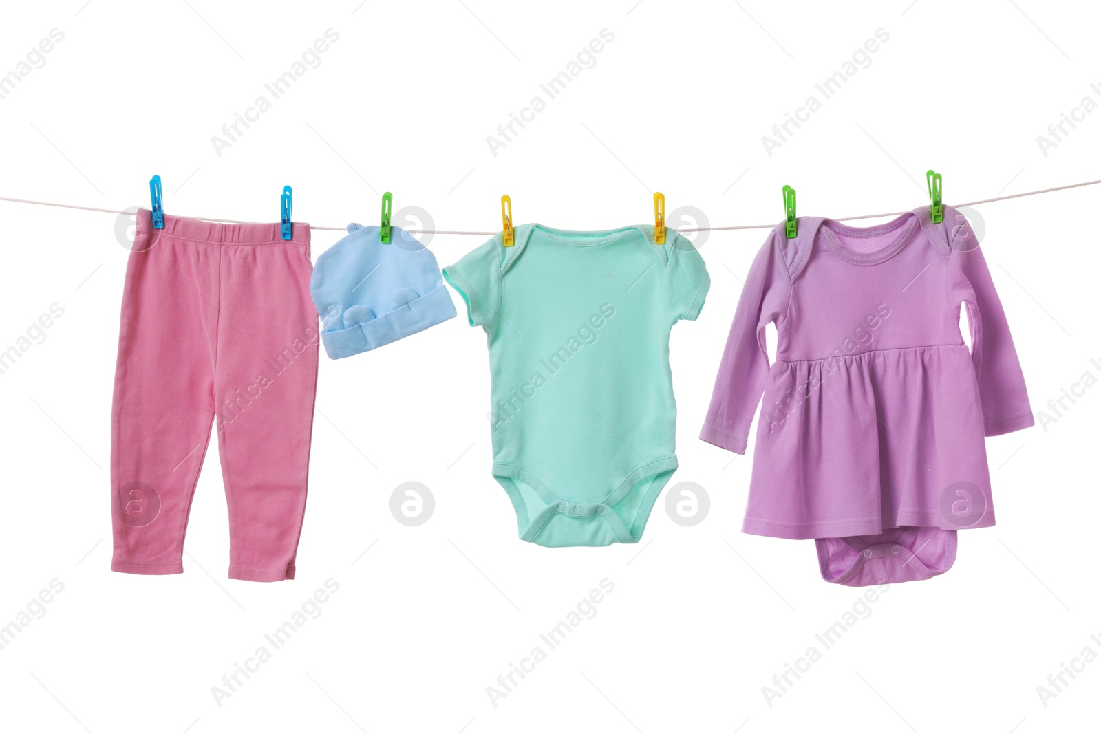 Photo of Different baby clothes drying on laundry line against white background