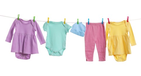 Different baby clothes drying on laundry line against white background