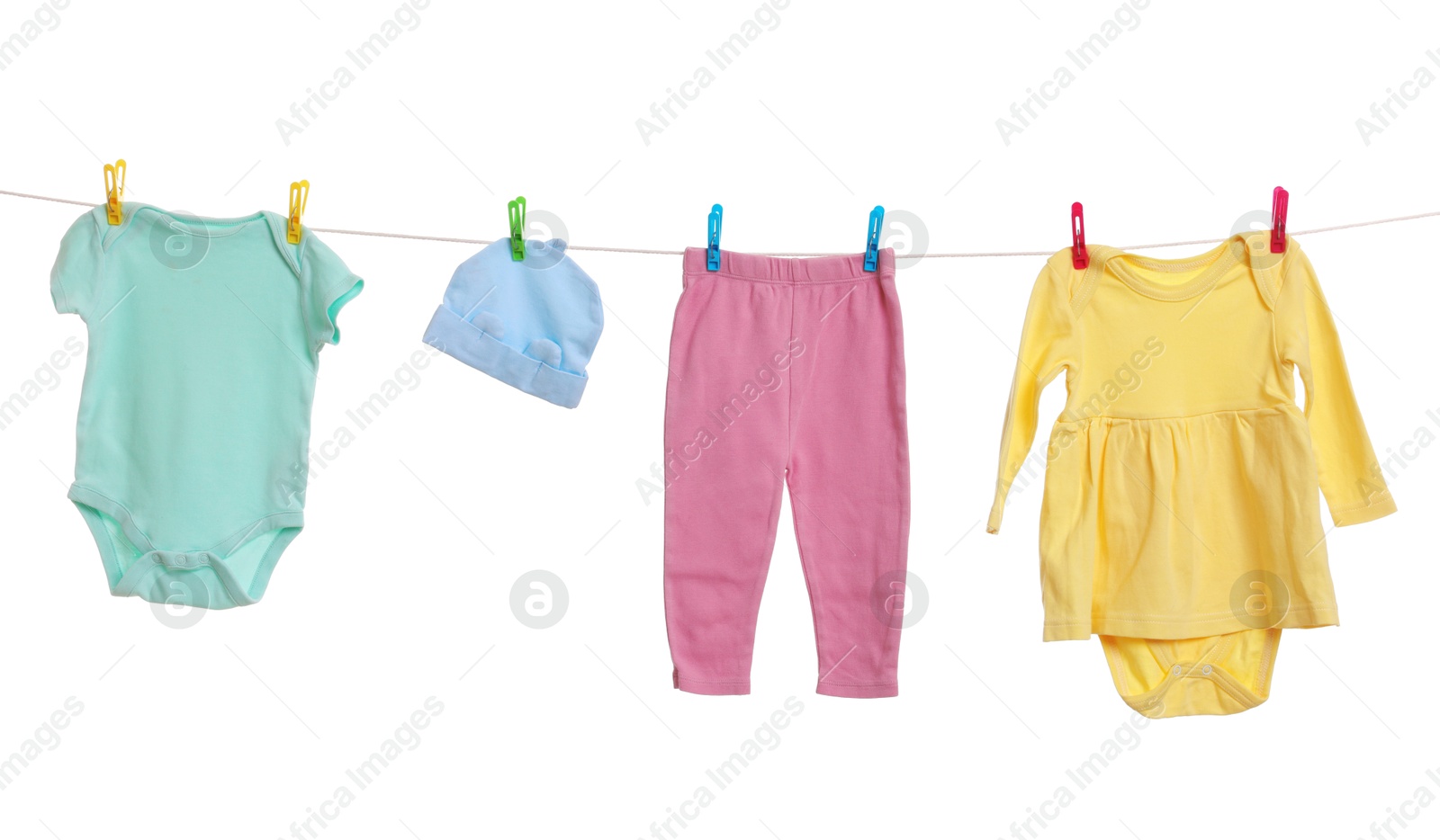 Photo of Different baby clothes drying on laundry line against white background