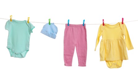 Photo of Different baby clothes drying on laundry line against white background