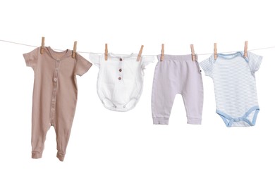 Different baby clothes drying on laundry line against white background