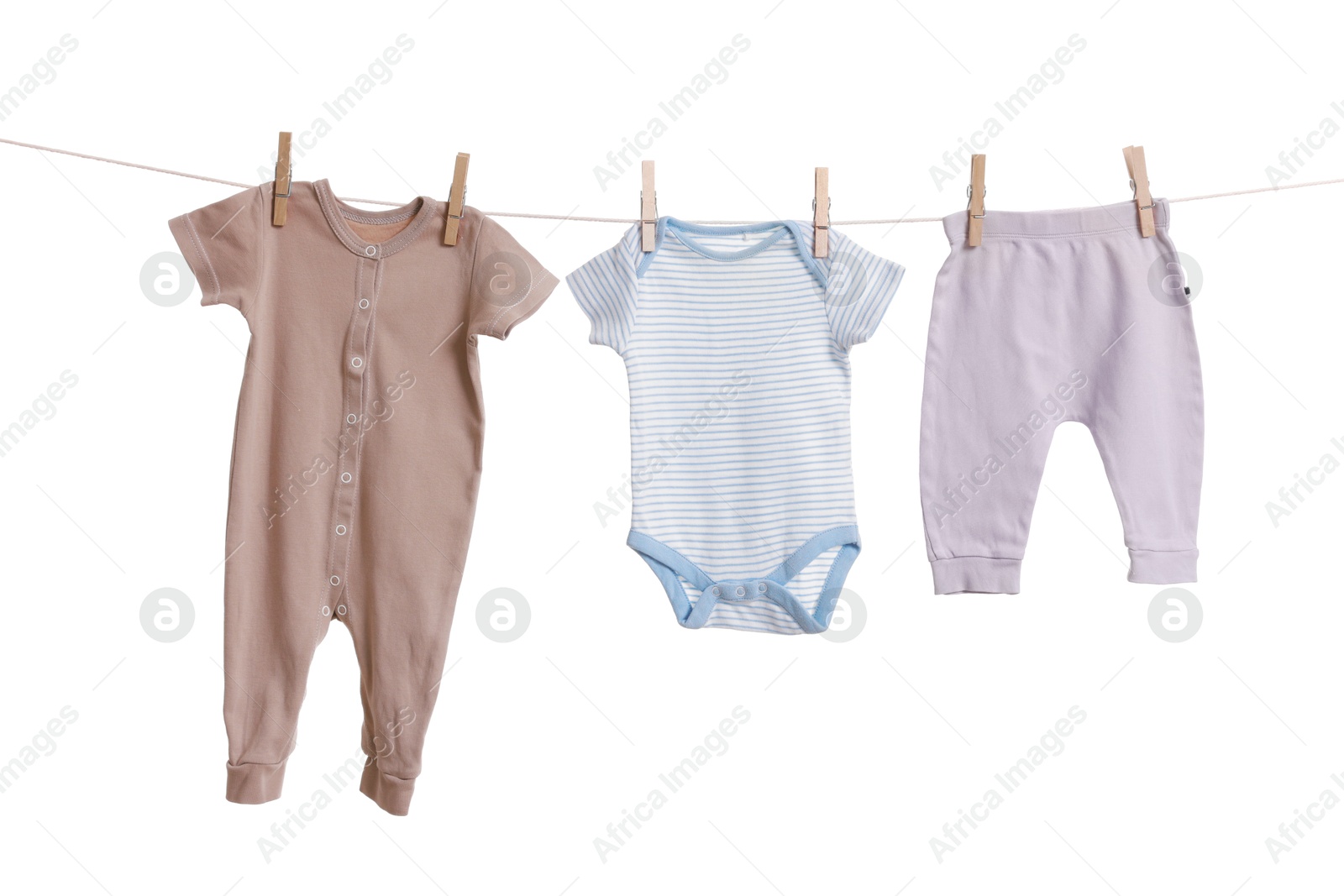 Photo of Different baby clothes drying on laundry line against white background