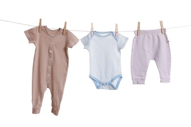 Photo of Different baby clothes drying on laundry line against white background