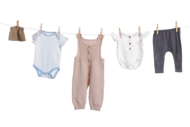 Photo of Different baby clothes drying on laundry line against white background