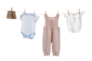 Different baby clothes drying on laundry line against white background