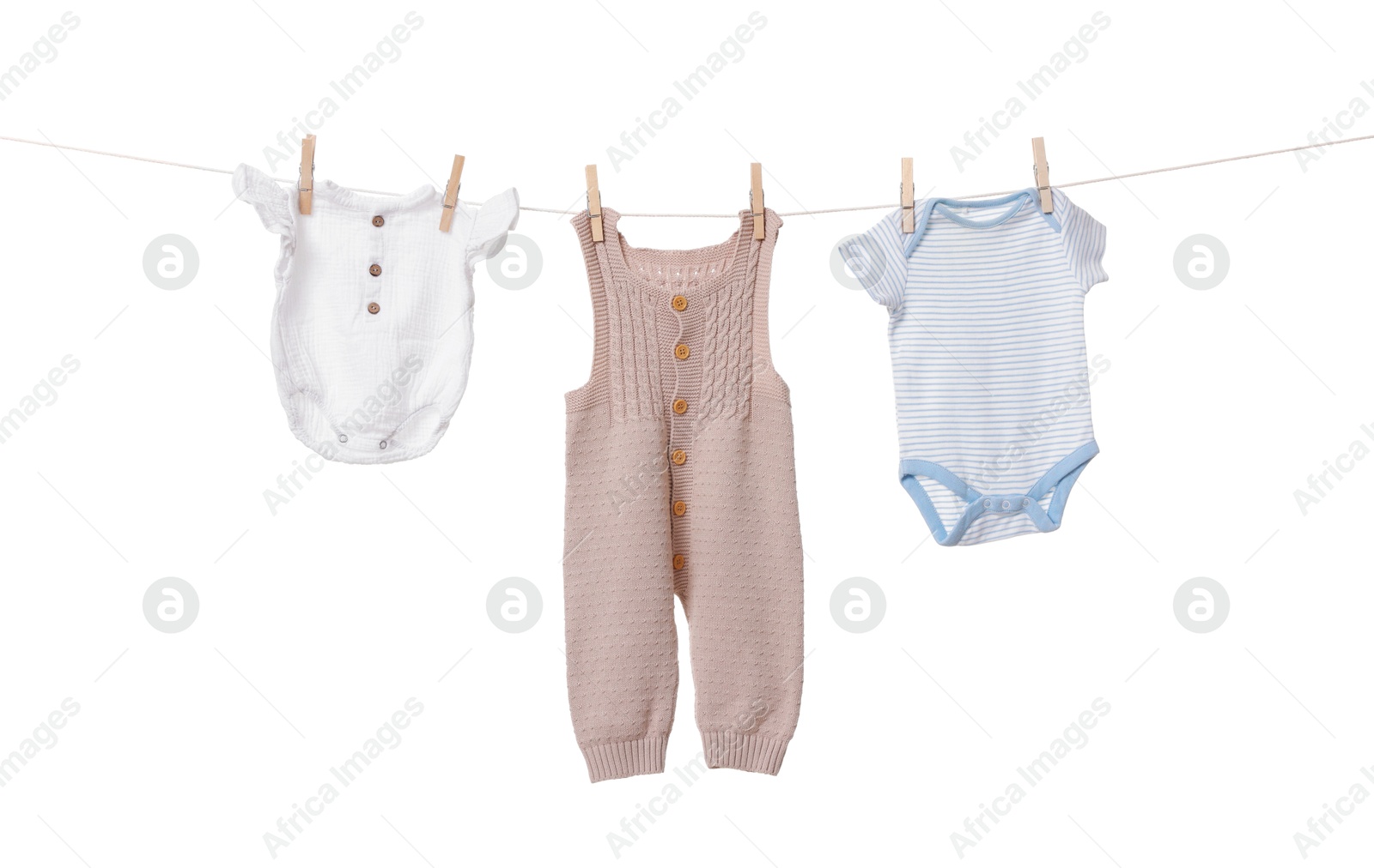 Photo of Different baby clothes drying on laundry line against white background