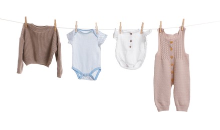 Photo of Different baby clothes drying on laundry line against white background