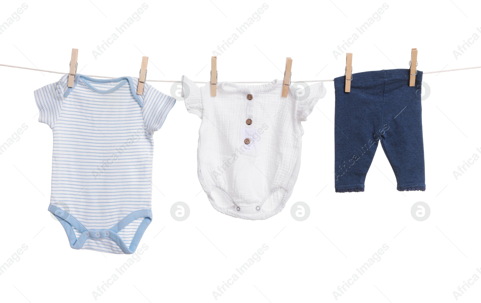 Photo of Different baby clothes drying on laundry line against white background