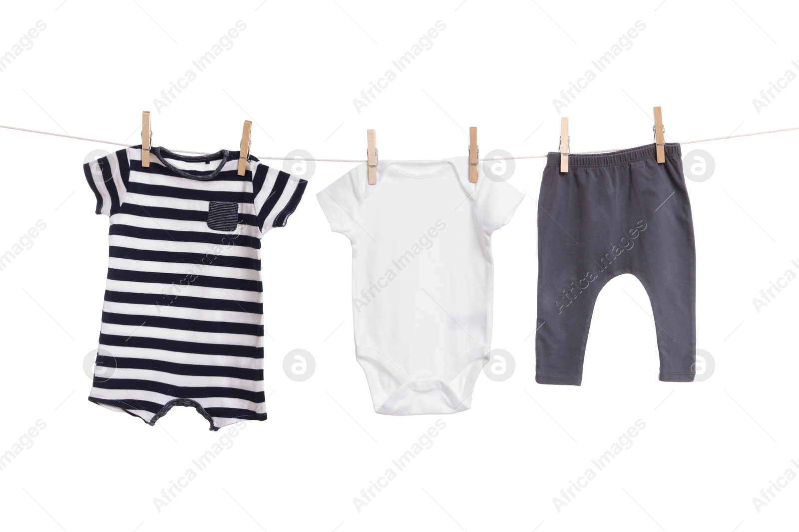 Photo of Different baby clothes drying on laundry line against white background